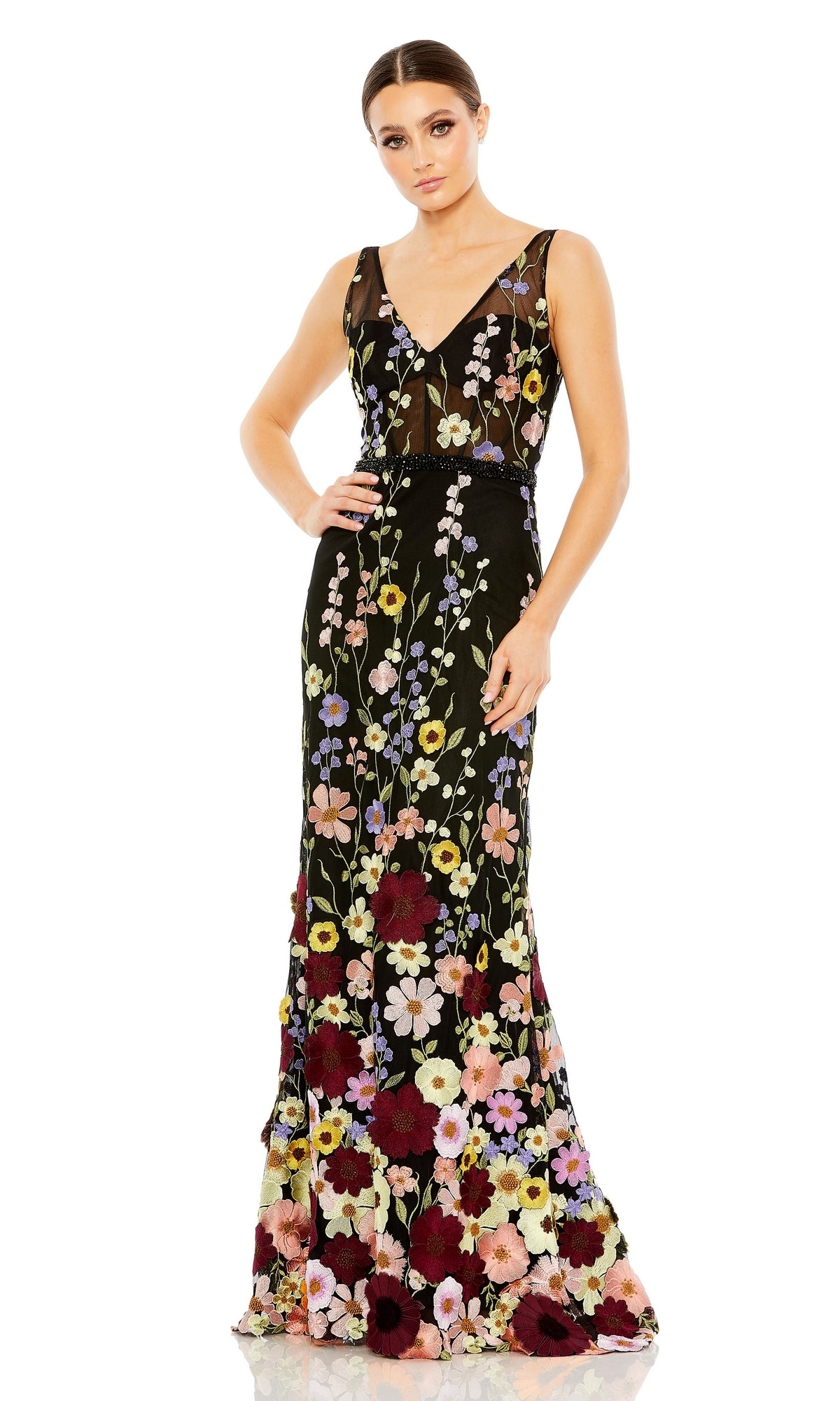 A woman stands wearing the Mac Duggal 68200 Floral Long Black Formal Dress, a sleeveless, floor-length gown with a V-neck and multicolored floral embroidery.
